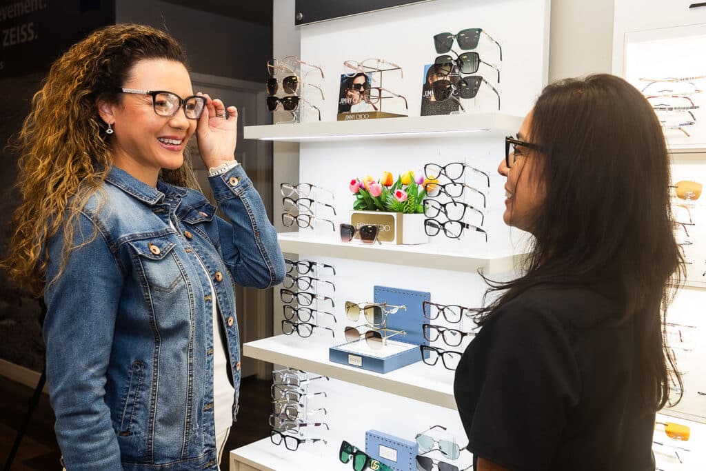 Woman trying on eyeglasses with the help of an optician